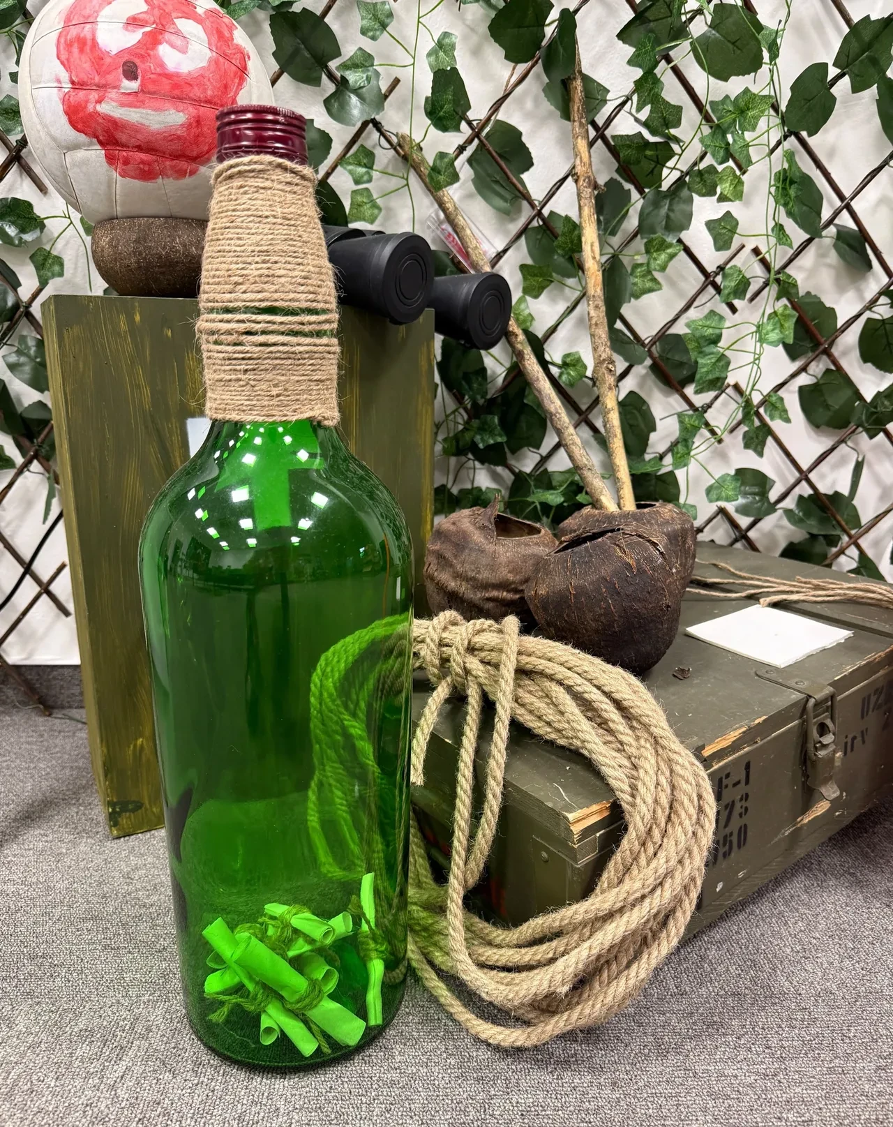 Green glass bottle filled with rolled message scrolls, beside a coil of rope